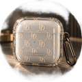 Clear Device District DD Monogram AirPods case with champagne gold pattern and dark carabiner